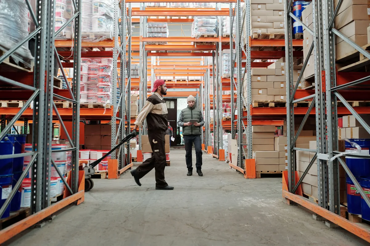 Warehouse workers in an aisle with a pallet jack